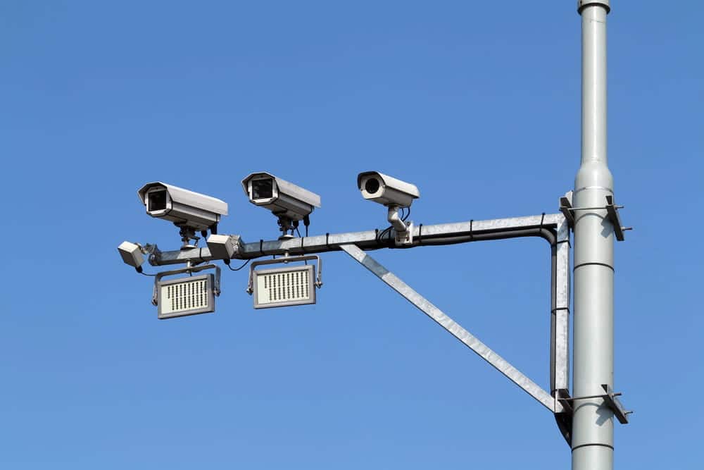 Image is of traffic surveillance cameras mounted above a roadway, concept of a pedestrian accident lawyer gathering video evidence after a collision.