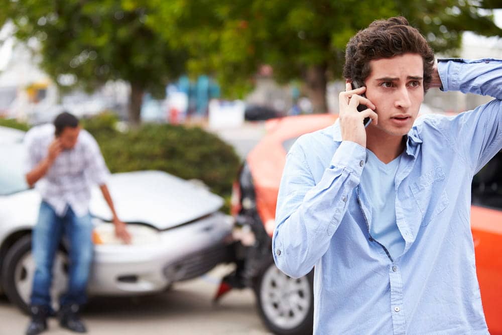 Image is of an individual calling for assistance after a motor vehicle collision, concept of a personal injury lawyer.