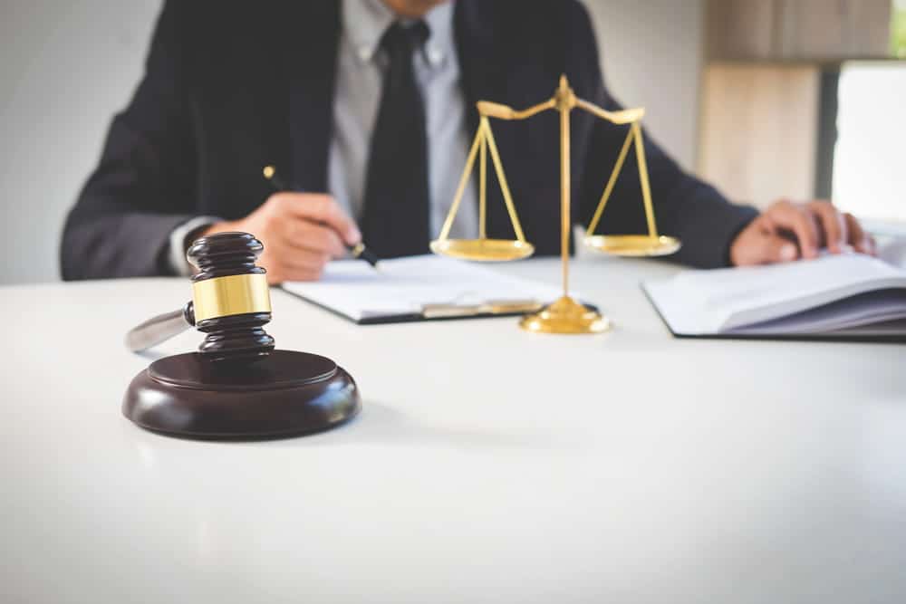 Image is of a person reviewing legal paperwork near a gavel, concept of an Aiken postnuptial agreement lawyer helping spouses evaluate financial responsibilities and marital agreements.
