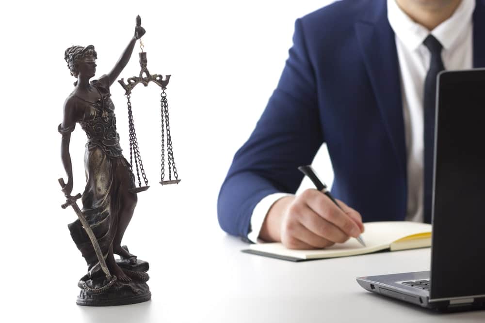 Image is of a lawyer working beside a Lady Justice statue, concept of an Aiken prenuptial agreement lawyer providing legal guidance regarding marital agreements and asset protection.