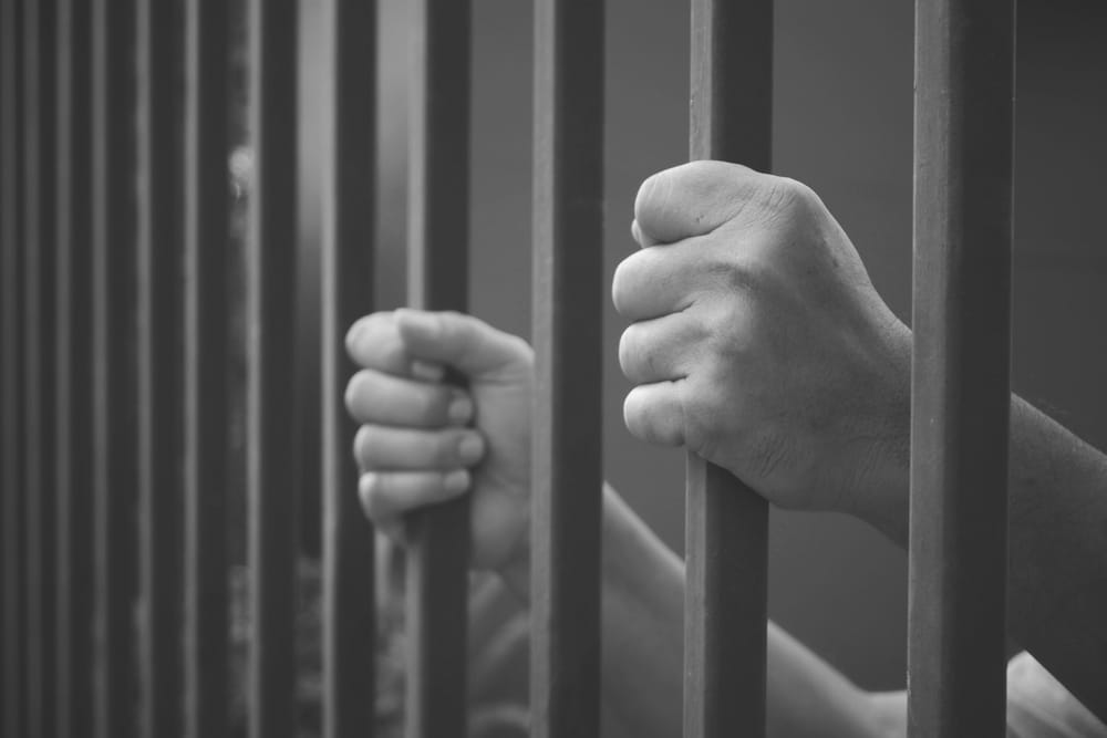 Image is of an individual holding prison bars, concept of an Aiken sex crimes lawyer defending against serious criminal allegations.