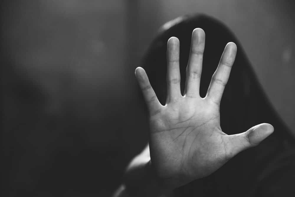 Image is of an individual raising a hand in a gesture of distress, concept of an Aiken sex crimes lawyer handling cases involving allegations of sexual misconduct.