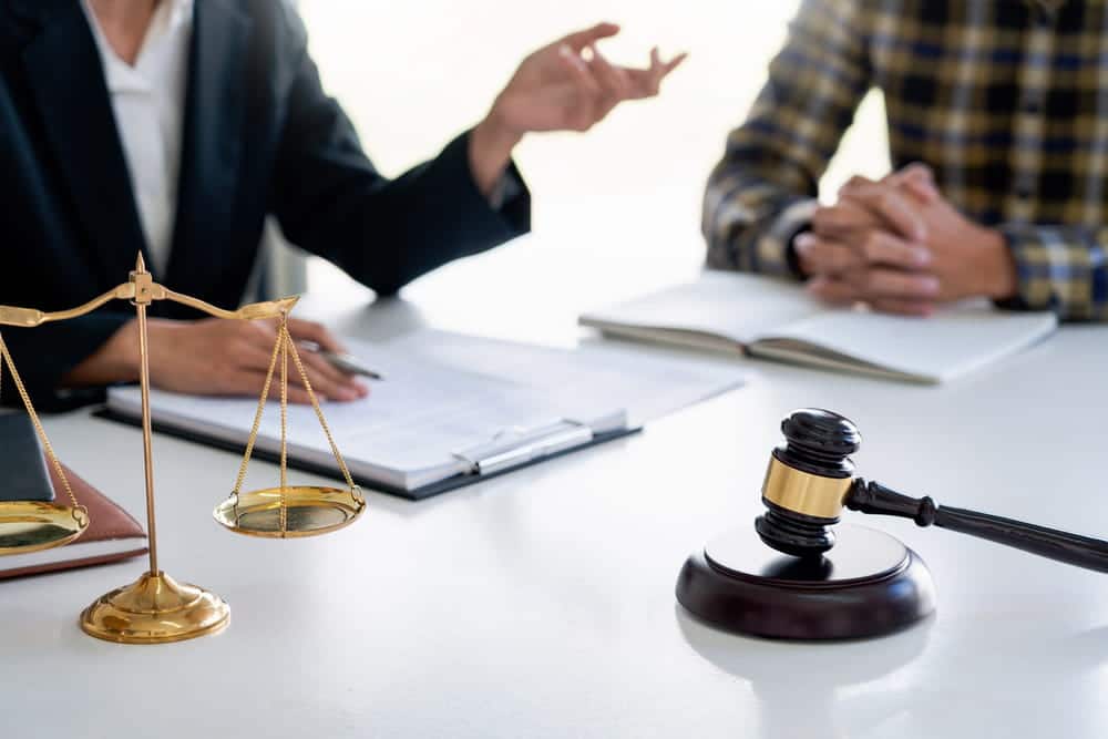 Image is of an attorney discussing legal matters with a client in an office setting, concept of an Aiken sexual assault lawyer providing case guidance and defense representation.