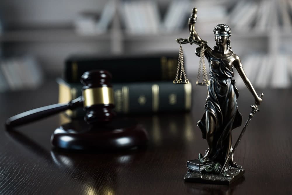 Image is of a judge's gavel and a Lady Justice statue on a courtroom desk, concept of an Aiken harassment and stalking lawyer representing clients in criminal court.