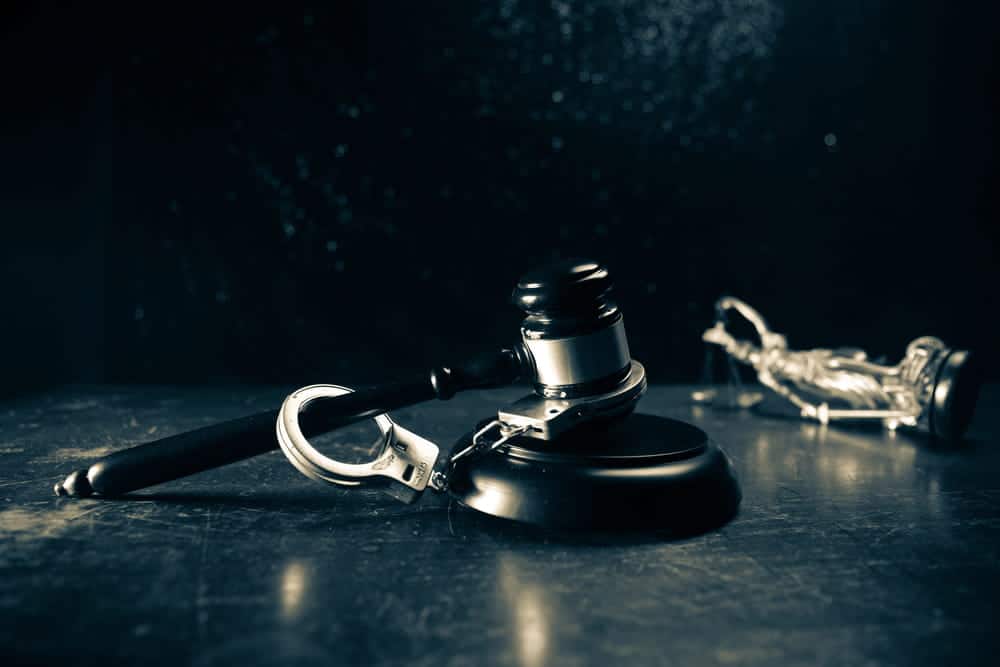 Image is of a courtroom gavel and handcuffs on a table, concept of an Aiken shoplifting lawyer representing individuals charged with shoplifting and related offenses.