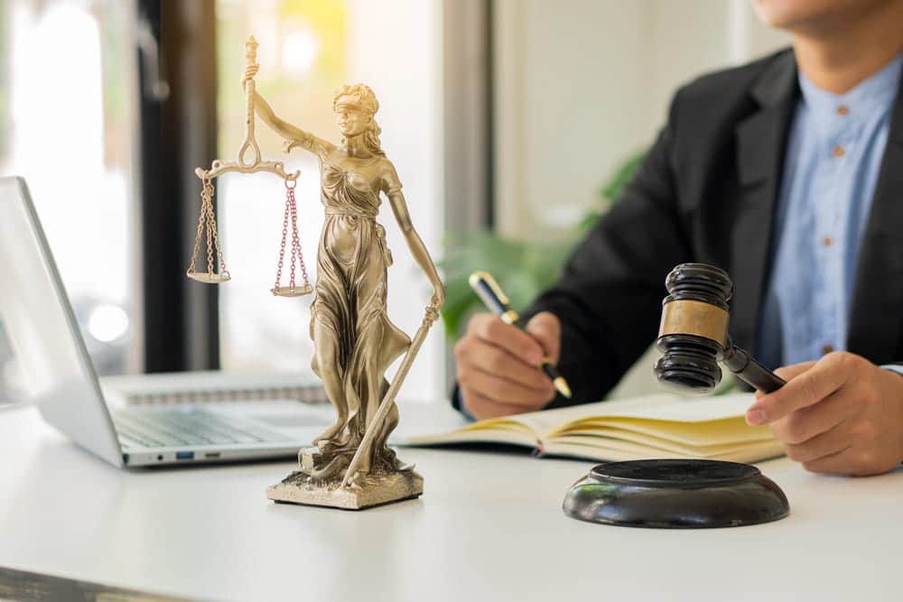 Image is of an attorney reviewing documents beside a gavel and Lady Justice statue, concept of an Aiken shoplifting lawyer advising clients facing theft-related allegations.