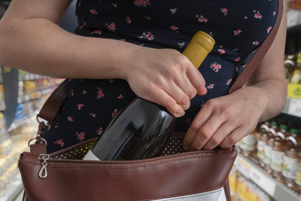age is of an individual placing merchandise into a handbag inside a store, concept of an Aiken shoplifting lawyer handling allegations involving retail theft and store property.