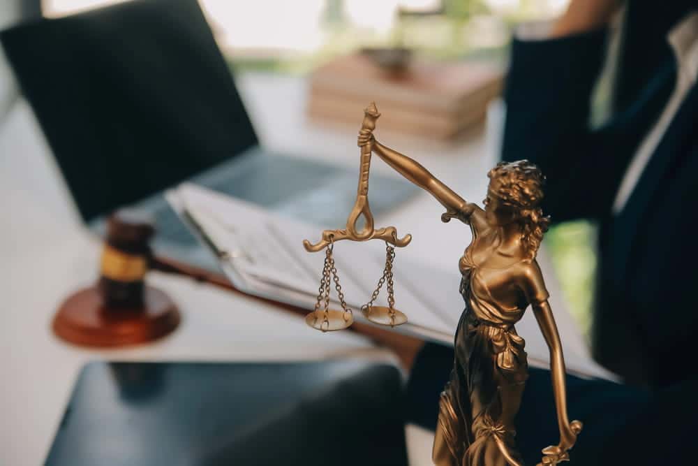 Image is of a Lady Justice statue beside legal documents, concept of a slip and fall lawyer evaluating liability and evidence in a premises liability claim.