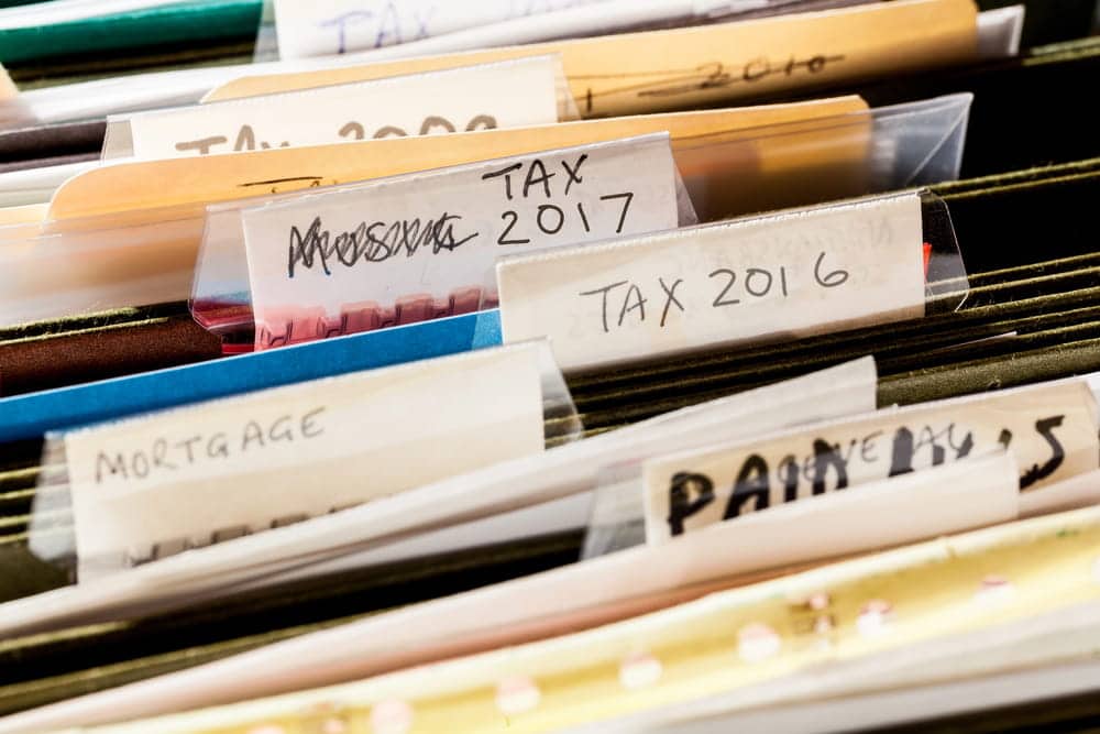 Image is of organized tax files and financial records in a filing cabinet, concept of an Aiken tax evasion lawyer reviewing tax documentation during a criminal investigation.