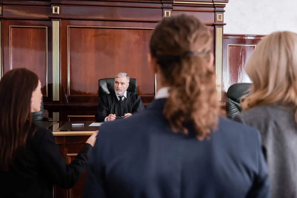 Image is of individuals appearing before a judge in a courtroom, concept of an Aiken traffic violations lawyer advocating for clients during traffic violation hearings.