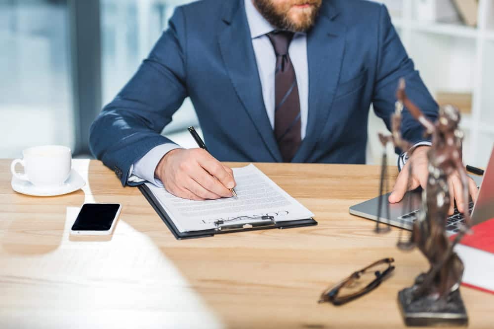 Image is of a lawyer reviewing legal documents at a desk, concept of an Uber accident lawyer helping clients pursue compensation after a rideshare crash.
