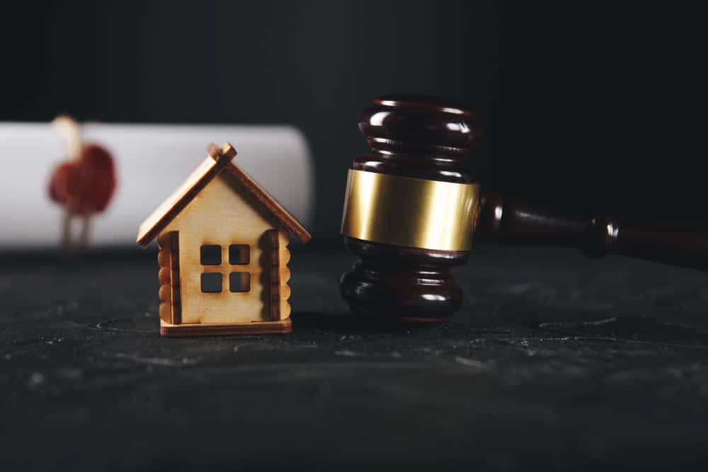 Image is of a house model beside a judge's gavel, concept of property agreement assistance from an uncontested divorce lawyer in Aiken.