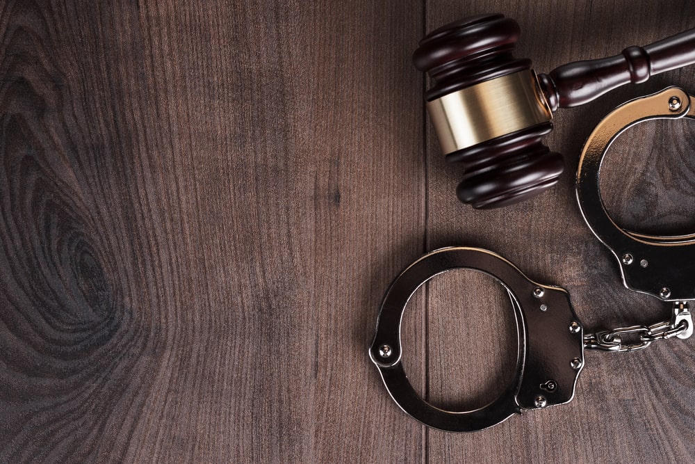Image is of a judge's gavel beside a pair of handcuffs on a wooden surface, concept of a violent crime lawyer defending individuals facing serious criminal charges.