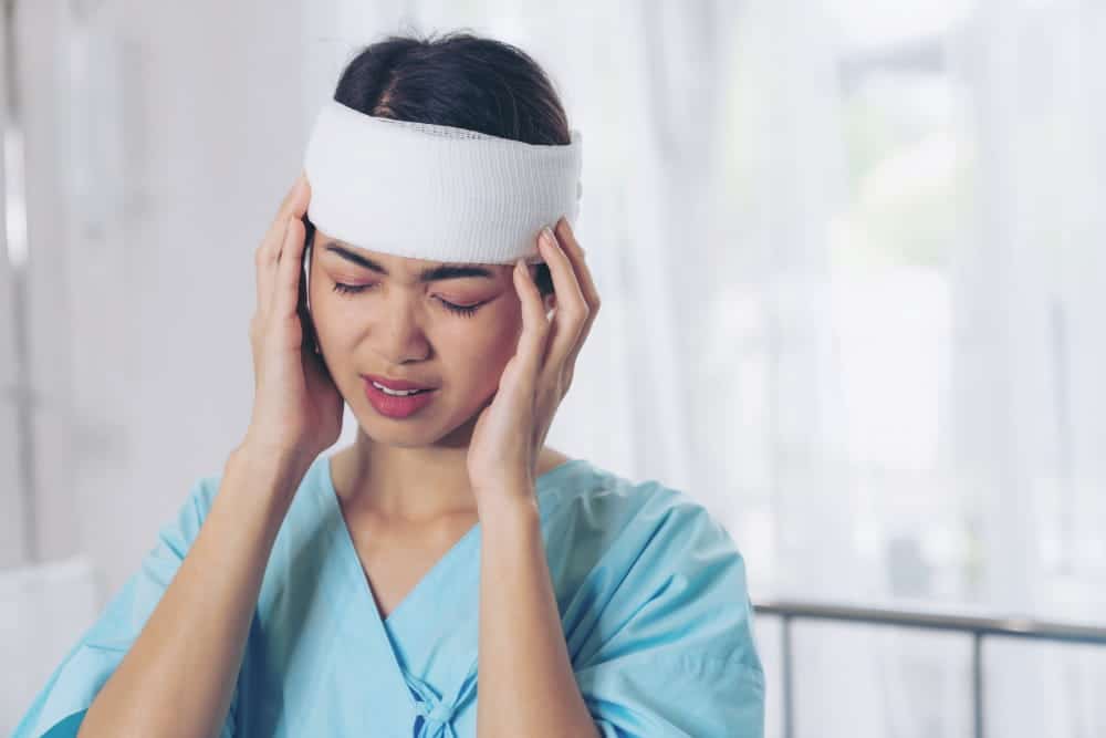 Image is of an injured worker experiencing head pain while recovering from an accident, concept of a workers' compensation lawyer assisting with workplace injury benefits.