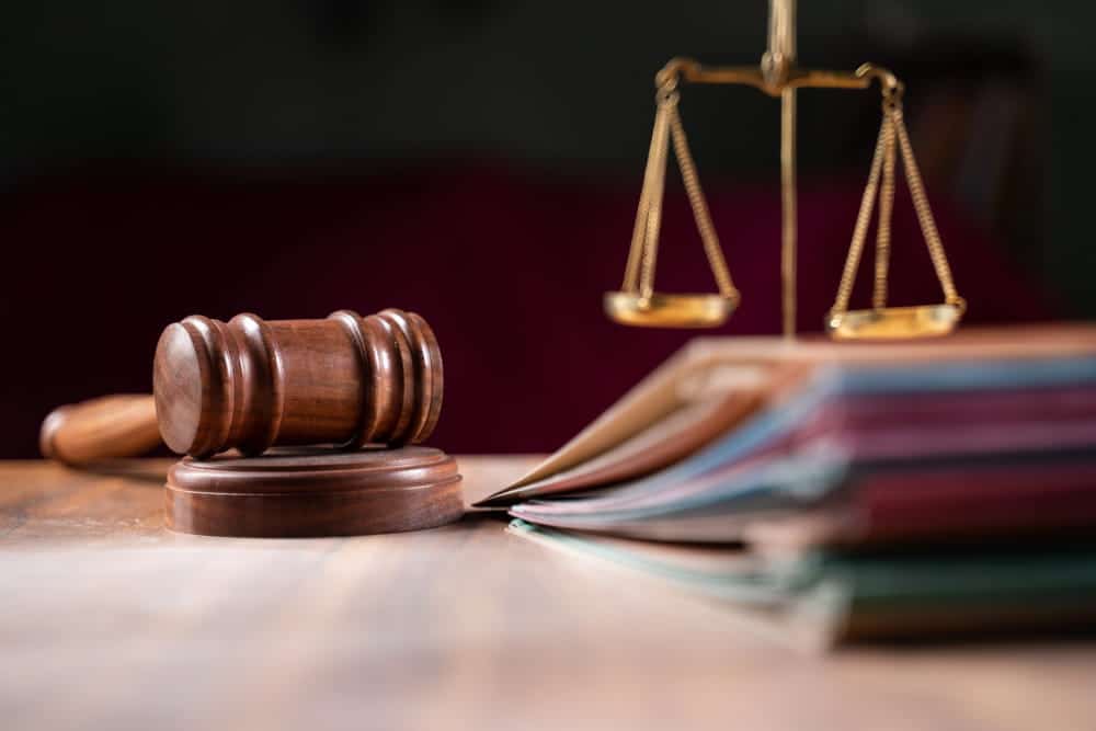 Image is of a gavel, legal files, and scales of justice on a desk, concept of a workers' compensation lawyer handling workplace injury claims.