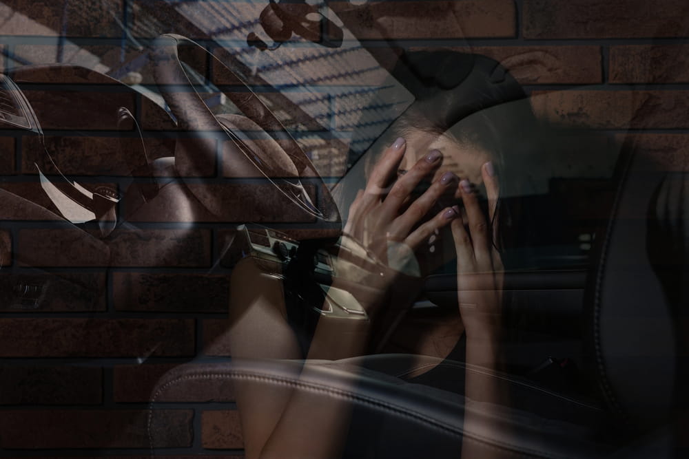 Image is of a person sitting in a vehicle and appearing emotionally distressed after a serious collision, concept of a wrongful death lawyer helping families after a fatal accident.