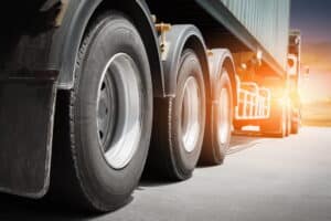 Image is of commercial truck tires and wheels on the road, showing vehicle components that require proper maintenance to help avoid truck accidents in Aiken.
