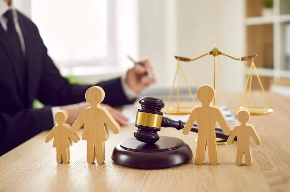 Image is of family figures, scales of justice, and a gavel on a desk, concept of child-related matters handled by a divorce lawyer in Aiken SC.