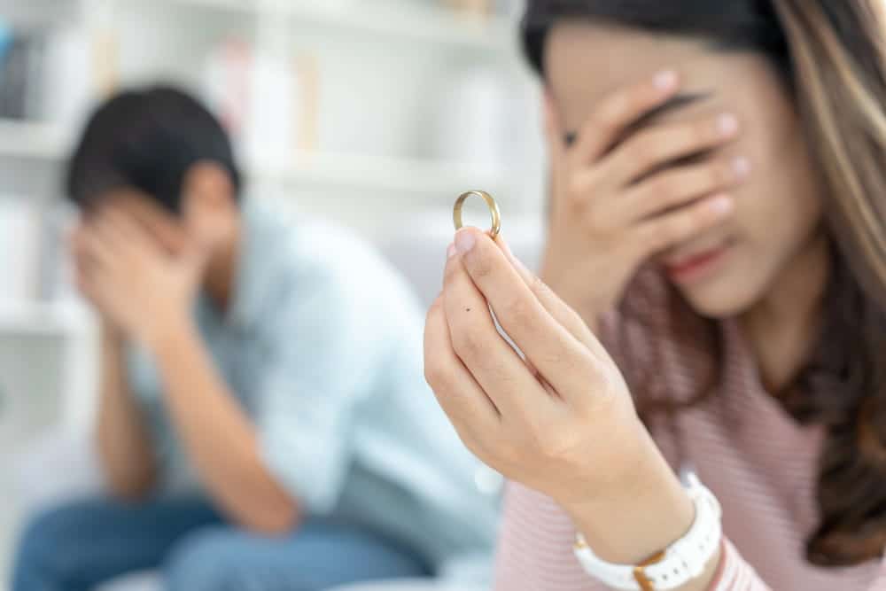 Image is of a woman holding a wedding ring while reflecting on the end of a marriage, concept of seeking guidance from a divorce lawyer in Aiken SC.