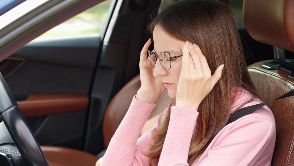 Image is of an individual sitting in a vehicle experiencing anxiety and emotional stress while driving after a car crash in Aiken.