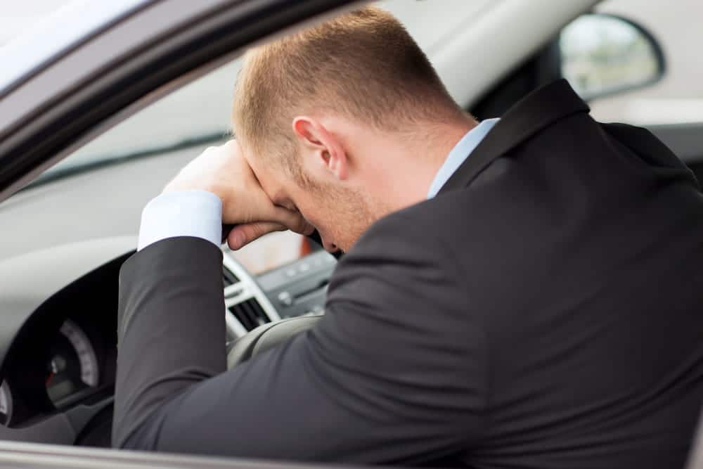 Image is of a driver sitting in a vehicle with visible emotional strain after an accident, concept of a car crash in Aiken.