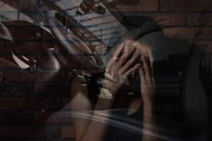 Image is of an individual sitting in a vehicle experiencing emotional distress and anxiety following a car crash in Aiken.