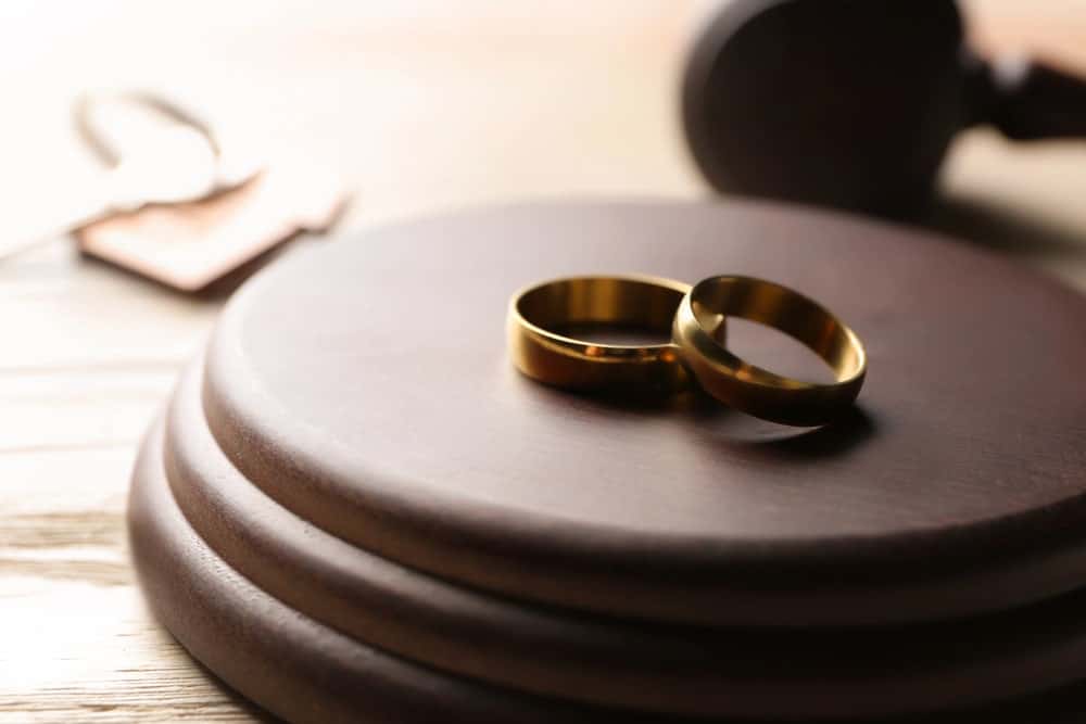 Image is of wedding rings resting on a judge's gavel block, concept of a family law attorney handling divorce and marital dissolution matters.