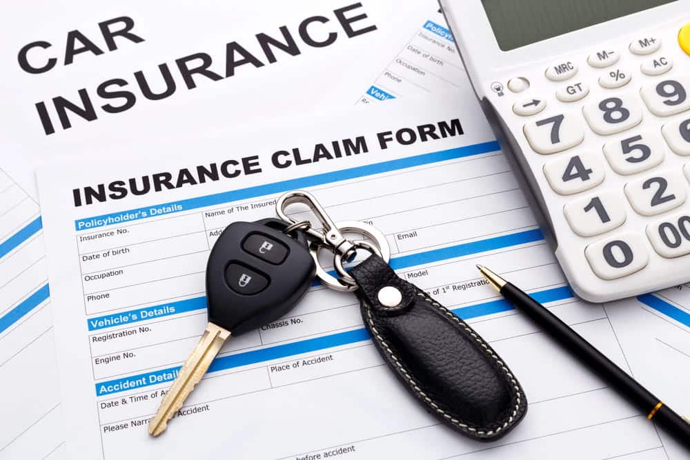 Image is of a car insurance claim form with vehicle keys after a car accident in Aiken, concept of filing an insurance claim.