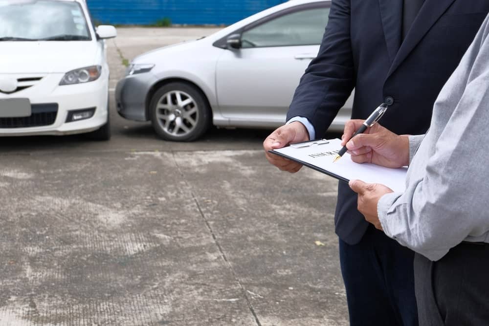 Image is of two people reviewing insurance documents after a car accident in Aiken, concept of documenting information for an insurance claim.