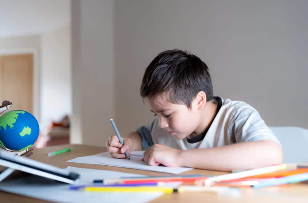 Image is of a child completing schoolwork at home, representing factors courts may consider when determining child custody.