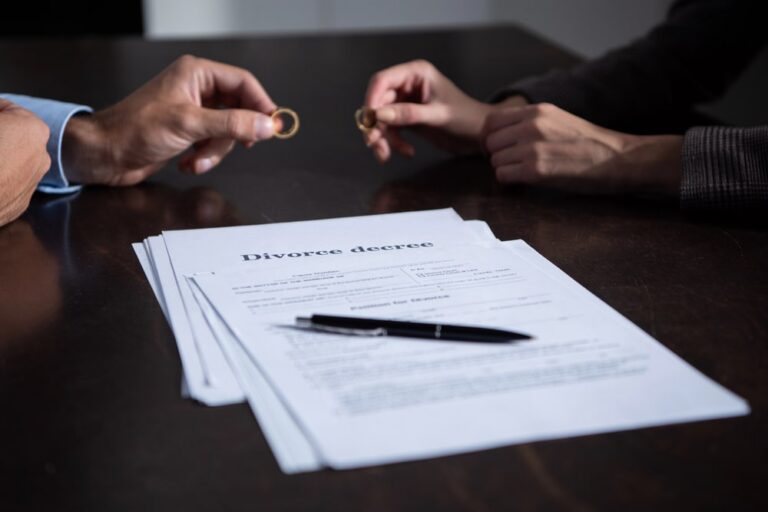 Image is of two spouses holding wedding rings over divorce paperwork during a legal meeting, concept of divorce proceedings in South Carolina.