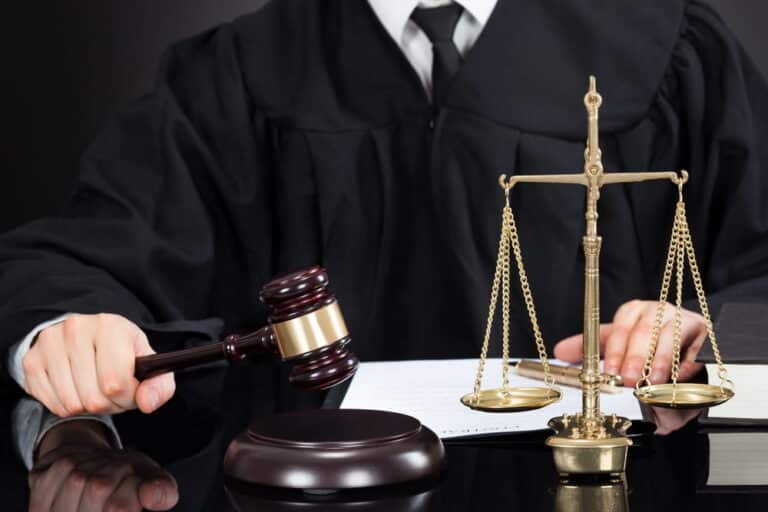 Image is of a judge's gavel and scales of justice on a courtroom desk, concept of order of protection