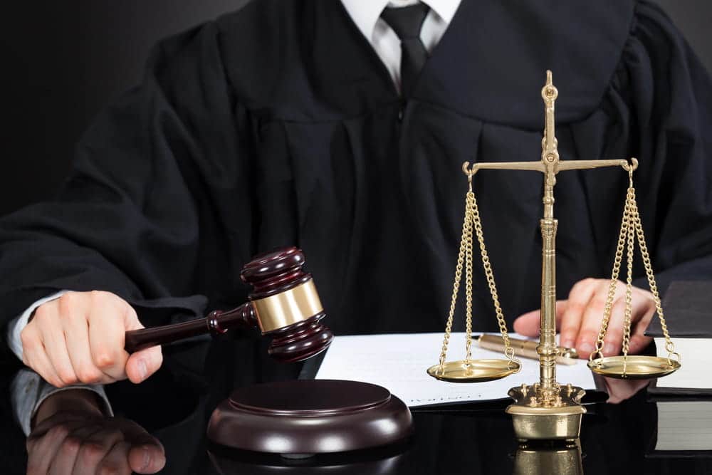 Image is of a judge's gavel and scales of justice on a courtroom desk, concept of order of protection