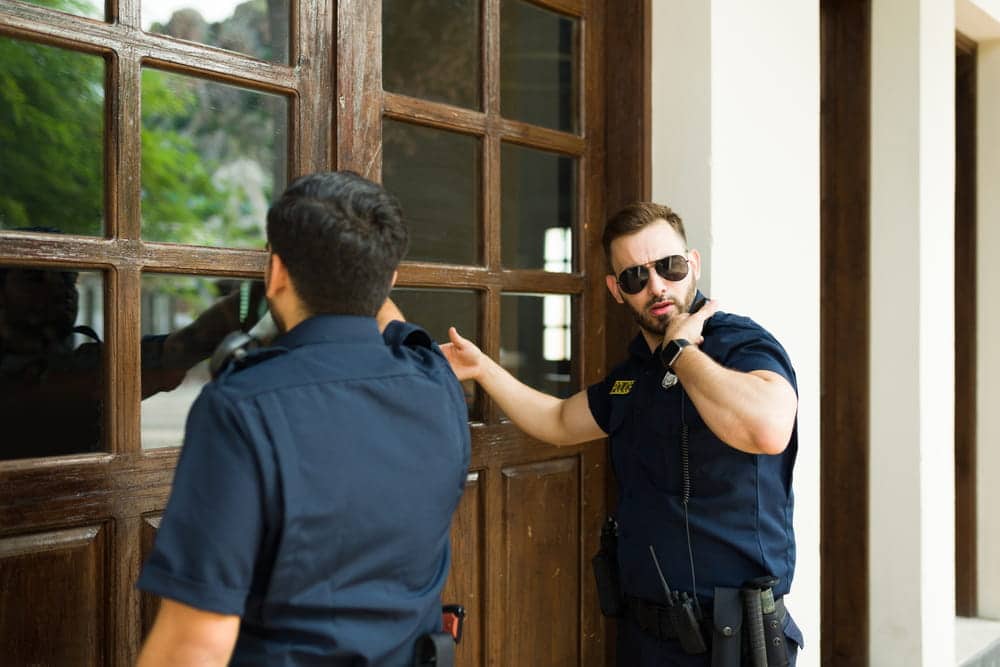 Image is of law enforcement officers serving documents at a residence, concept of order of protection