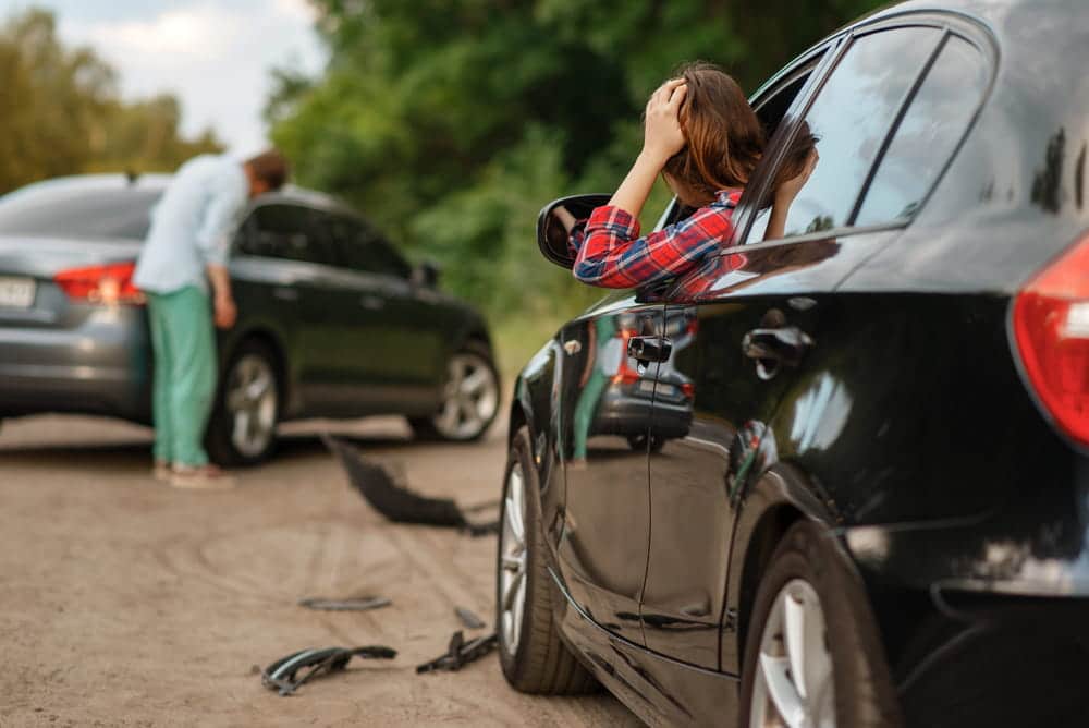 Image is of drivers standing near damaged vehicles after a collision, concept of car accident injuries in Aiken.