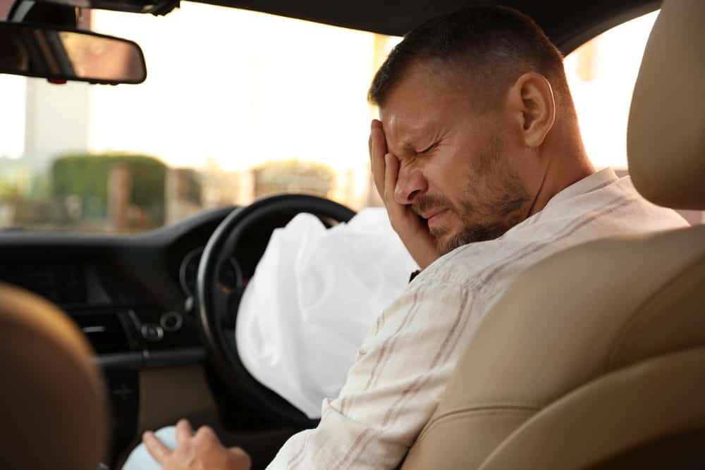 Image is of a driver experiencing head pain after airbag deployment, concept of car accident injuries in Aiken.