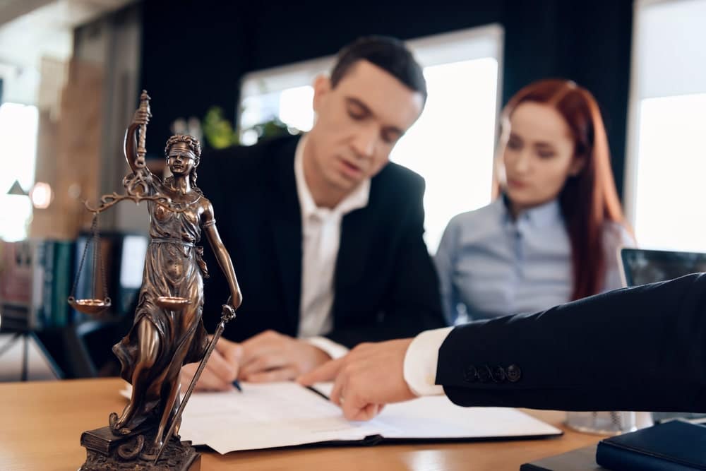 Image is of a couple reviewing legal documents with a lawyer, concept of how property divided in South Carolina divorce cases.