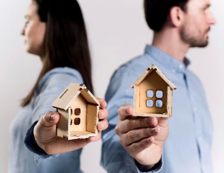Image is of a separating couple holding individual model homes, concept of how property divided during divorce in South Carolina.