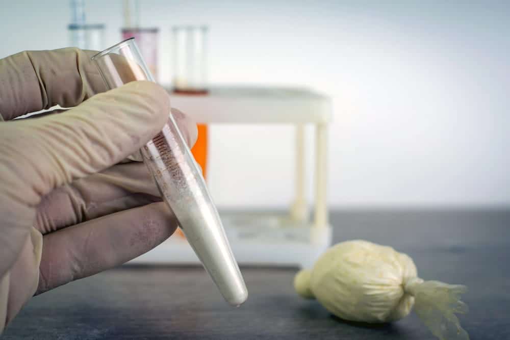 Image is of a laboratory technician examining a substance sample, representing evidence testing in drug cases in Aiken.