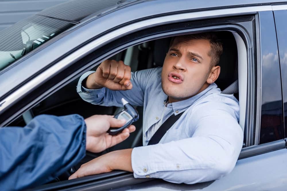 Image is of a driver speaking with an officer holding a breathalyzer, concept of a failed breath test in Aiken.