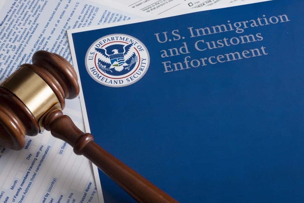 Image is of a judge’s gavel beside immigration enforcement documents, representing how domestic violence may affect immigration status.