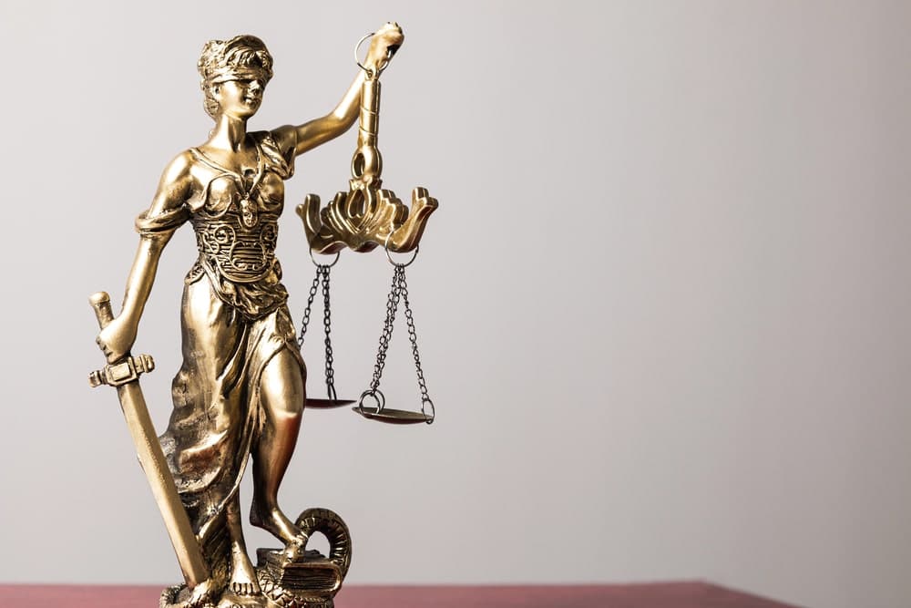 Image is of a Lady Justice statue holding scales, representing legal consequences of domestic violence for immigration status.