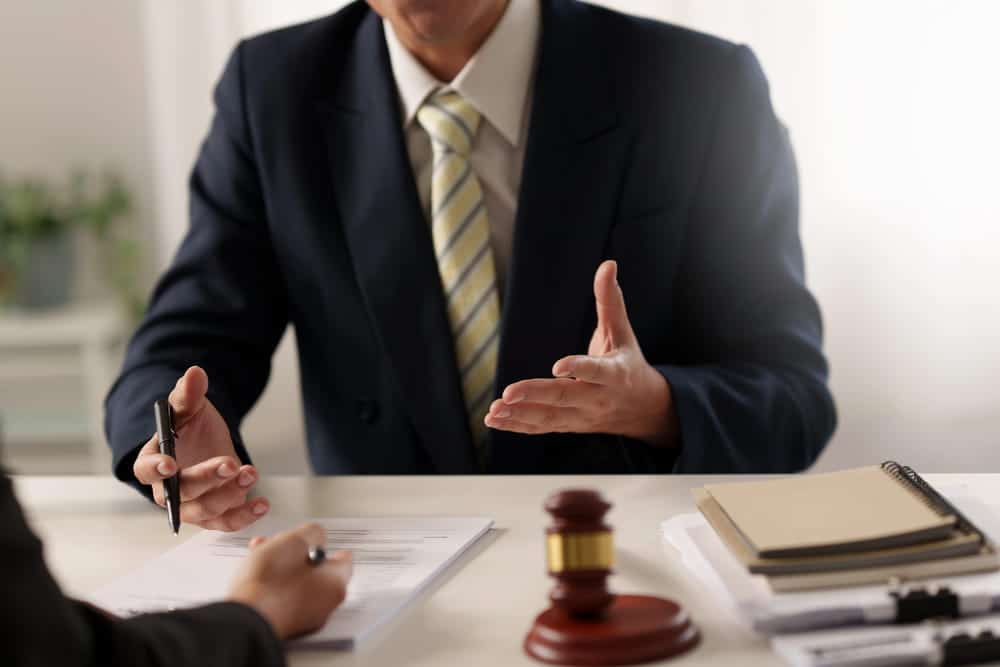 Image is of a lawyer discussing a case with a client beside legal scales and a gavel, concept of a DUI case in Aiken.