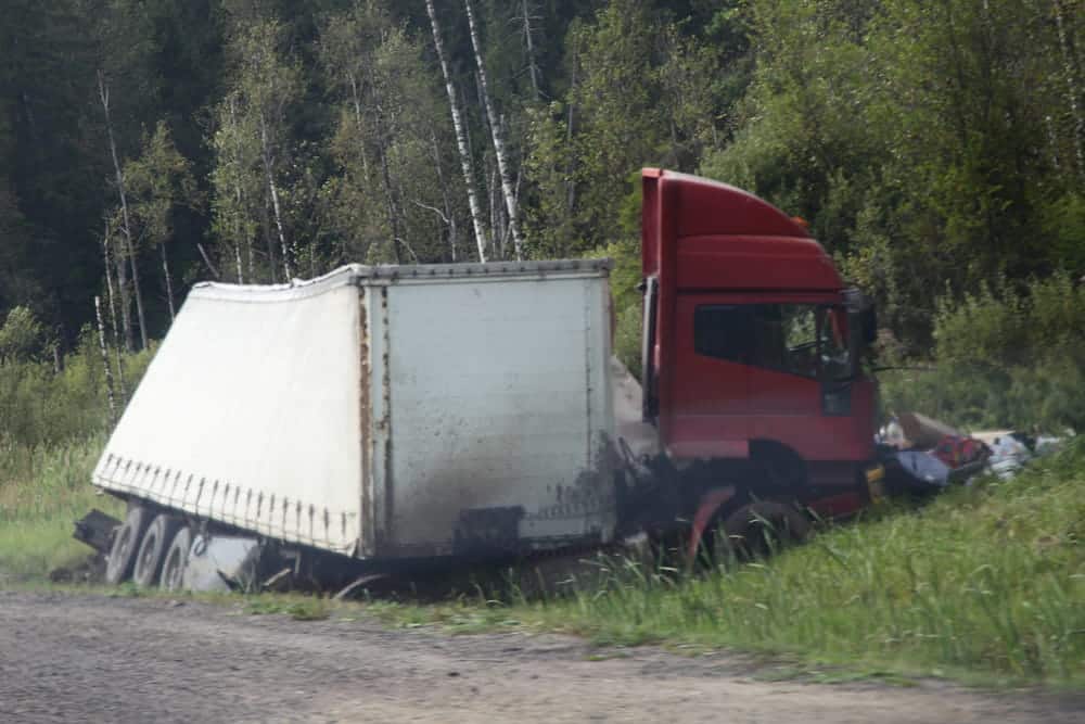 Image is of a commercial truck crashed off the roadway, concept of a jackknife truck accident in Aiken.