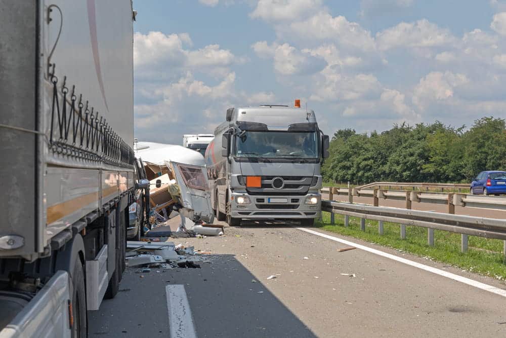 Image is of commercial trucks at a highway crash scene, showing evidence that may affect a truck accident settlement.