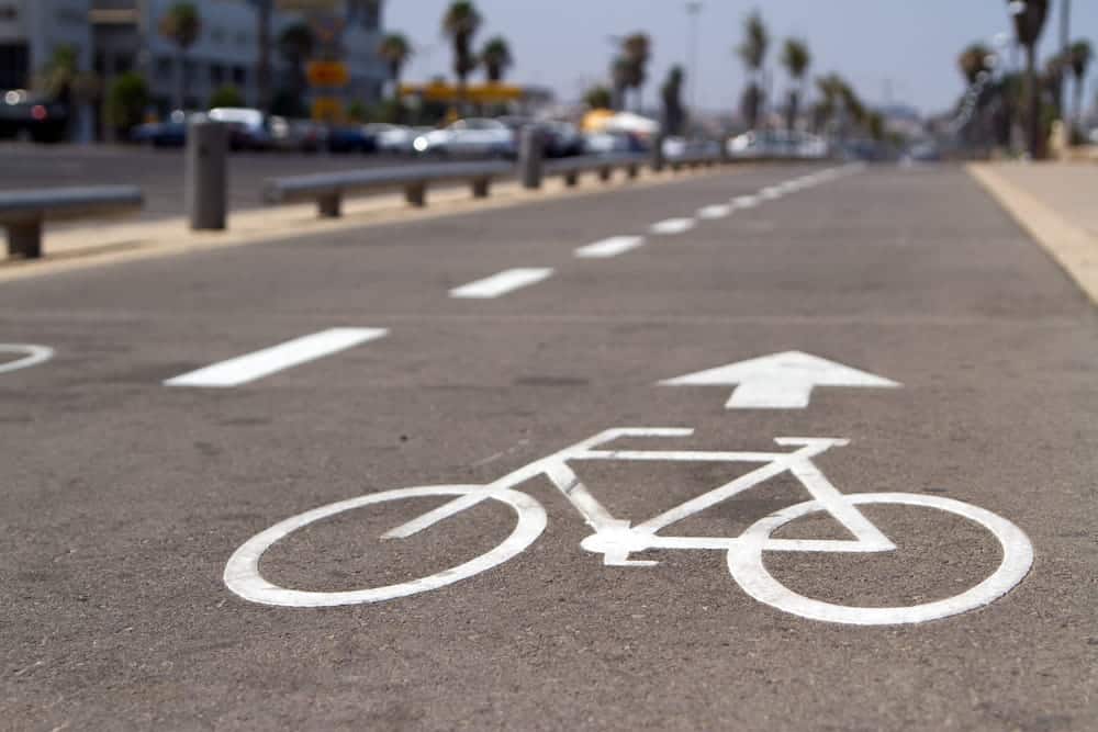 Image is of a bicycle symbol and directional arrow painted on a roadway, concept of right of way rules for cyclists and drivers.