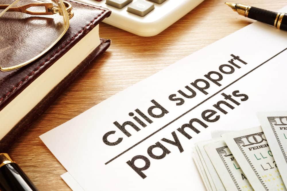 Image is of child support payment documents with money and a calculator, concept of financial changes affecting a child support order.