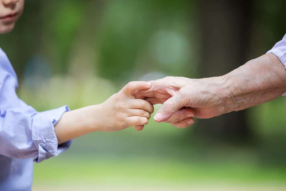 Image is of a grandparent holding a child’s hand, concept of when grandparents seek visitation to maintain a relationship with grandchildren.