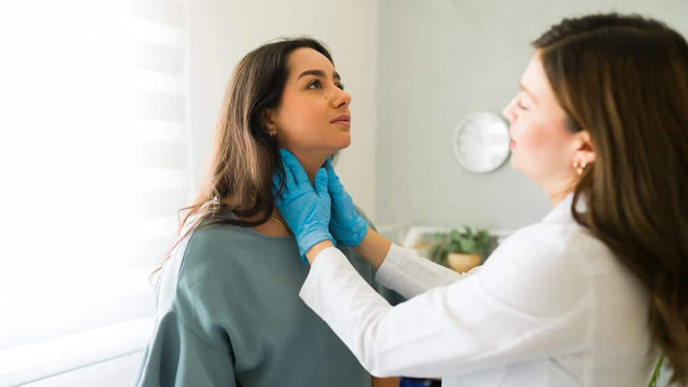 Image is of a doctor examining a patient's neck for symptoms that appeared after a car accident in Aiken.