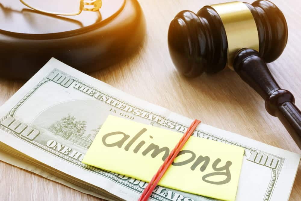 Image shows a judge's gavel beside cash labeled alimony, representing financial support and modification issues related to Underage divorce in Aiken.